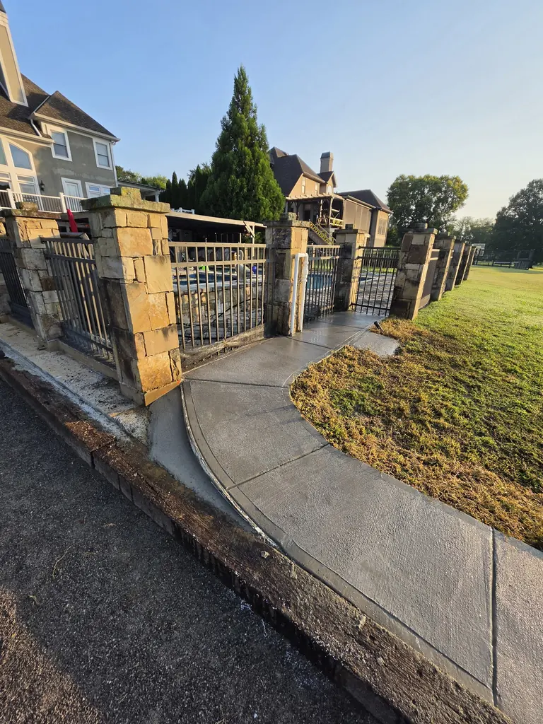 Curved concrete walkway finished at an iron gate entrance in Knoxville, Tennessee